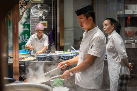 Xian, China -  August 2019 : Chinese chef preparing hot food on a food stall operating at night on the street in the Muslim Quarterのeditorial素材