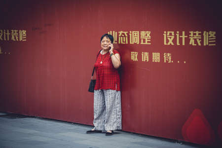 Chengdu, China -  July 2019 : Street scene in the city of Chengdu in summer, woman talking on her mobile phone, Sichuan Provinceのeditorial素材