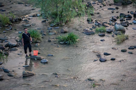 Wulingyuan, China -  August 2019 : Chinese fisherman standing in a shallow riverのeditorial素材