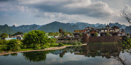 Wulingyuan, China - August 2019 : Riverside buildings with the stunningly beautiful rocky karst mountain formations behind as seen from the centre of  town, Hunan Provinceのeditorial素材