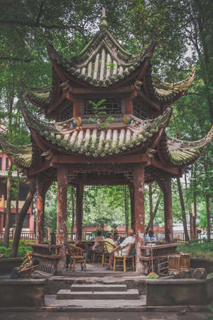 Chengdu, China -  July 2019 : Older senior people sitting on wicker chairs under pagoda roof and relaxing in the Chinese garden in the Wenshu Monastery, Sichuan Provinceのeditorial素材