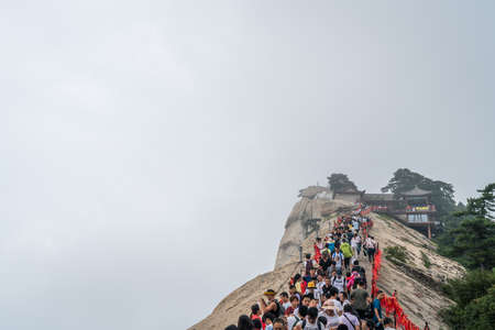 Huashan, China -  August 2019 : Crowds of tourists walking on a narrow ridge on a mountain trail to the West Peak on Huashan mountain, Xian, Shaanxi Provinceのeditorial素材