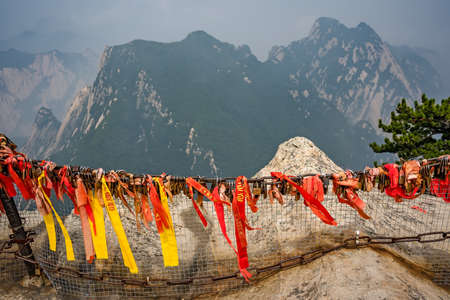 Huashan, China -  August 2019 : Red and yellow ribbons attached to the protective barrier on a lookout with the stunning mountain landscape view from the summit of West Peak, Huashan mountain, Shaanxi Provinceのeditorial素材