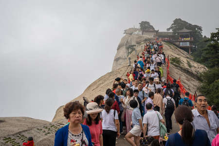 Huashan, China -  August 2019 : Crowds of tourists walking on a narrow ridge on a mountain trail to the West Peak on Huashan mountain, Xian, Shaanxi Provinceのeditorial素材