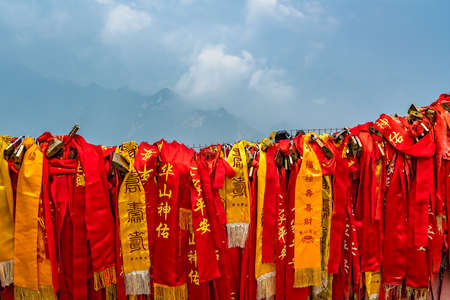 Huashan, China -  August 2019 : Red and yellow ribbons attached to the protective barrier on a lookout with the stunning mountain landscape view from the summit of West Peak, Huashan mountain, Shaanxi Provinceのeditorial素材