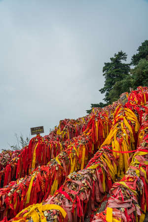 Huashan, China -  August 2019 : Memorial and religious symbolic red ribbons and locked padlocks tied to the barriers along the walking path in Huashan mountain,  Shaanxi Provinceのeditorial素材