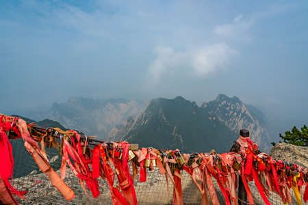 Huashan, China -  August 2019 : Red and yellow ribbons attached to the protective barrier on a lookout with the stunning mountain landscape view from the summit of West Peak, Huashan mountain, Shaanxi Provinceのeditorial素材