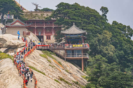 Huashan, China -  August 2019 : Crowds of tourists walking on a narrow ridge on a mountain trail to the West Peak on Huashan mountain, Xian, Shaanxi Provinceのeditorial素材