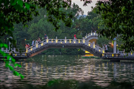 Guilin, China -  August 2019 : People and tourists walking on the bridge and walkway on a lake Shan Lake in the evening, Guilin town, Guangxi Provinceのeditorial素材