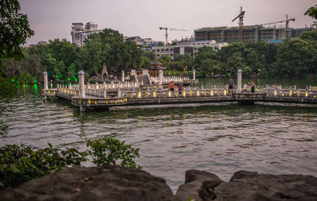 Guilin, China -  August 2019 : People and tourists walking on the bridge and walkway on a lake Shan Lake in the evening, Guilin town, Guangxi Provinceのeditorial素材