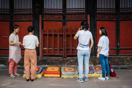 Chengdu, China -  July 2019 :  Four women preparing for a prayer in front of colorful praying kneeling pads in the courtyard of the Buddhist Wenshu Monastery, Sichuan Provinceのeditorial素材