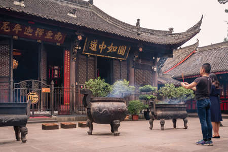 Chengdu, China -  July 2019 : Chinese woman and man praying, worshiping, burning incense sticks, giving alms and thanks at the Wenshu Chinese Buddhist Templeのeditorial素材