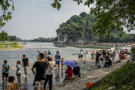 Guilin, China -  August 2019 : Crowds of people on the riverbank in summer in the extremely popular Park with Elephant Trunk Hill Arch and the Li Lijiang River in Guilin, Guangxi Provinceのeditorial素材