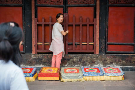 Chengdu, China -  July 2019 :  Chinese woman preparing for a prayer in front of colorful praying kneeling pads in the courtyard of the Buddhist Wenshu Monastery, Sichuan Provinceのeditorial素材