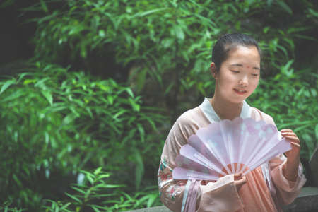 Chengdu, China -  July 2019 :  Portrait of a young asian chinese bride holding a fan at wedding ceremony in the parkのeditorial素材