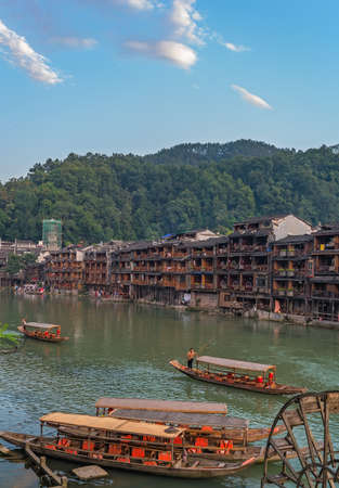 Feng Huang, China -  August 2019 : Old historic wooden tourist boats on the riverbanks of Tuo river, flowing through the centre of Fenghuang Old Townのeditorial素材