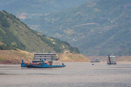 Yangtze River, China - August 2019 : Cargo ship ship transporting trucks and other vehicles sailing through the gorge on the magnificent Yangtze Riverのeditorial素材