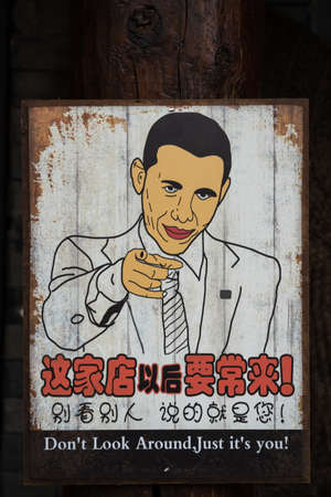 Wulingyuan, China - August 2019 : Wooden poster board with Barrack Obama lookalike and chinese characters writingのeditorial素材