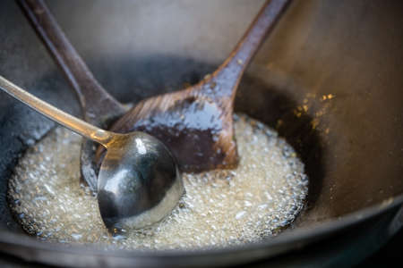 Three large ladles inside a metal pan full of hot boiling oil on a street food stall in Chinaの写真素材