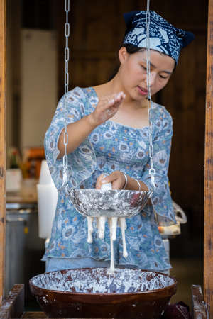 Feng Huang, China -  August 2019 : Woman making traditional chinese noodles on the food stall in...