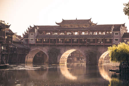 Feng Huang, China -  August 2019 : Morning view of the old historic arched bridge on the riverbanks...