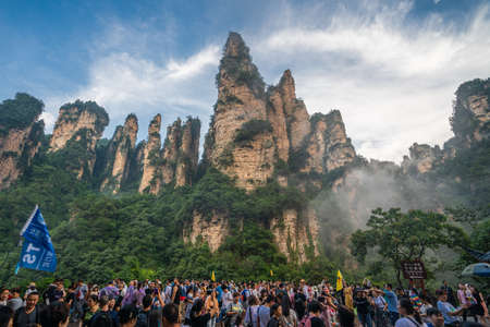 Zhangjiajie, China - August 2019 : Massive tourist crowds on the square at the bottom of Bailong Elevator lift with the Soldiers Gathering peaks behind, Avatar mountains nature parkのeditorial素材