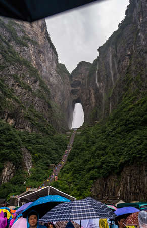 Zhangjiajie, China -  August 2019 : Massive tourist crowds waiting in torrential monsoon rain for public transport mini buses at the foot of Tianmen Mountain, the Zhangjiajie National Park, Hunan Provinceのeditorial素材