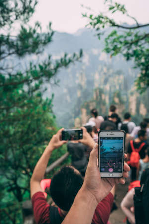 Zhangjiajie, China - August 2019 : Tourists taking pictures on mobile phones on the viewpoint in Tianzi mountain range, Avatar mountains nature parkのeditorial素材
