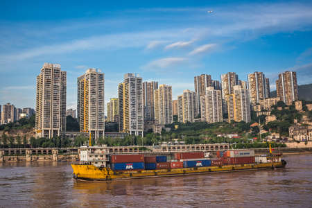 Chongqing, China - August 2019 : Huge cargo ship transporting large shipping containers departing...