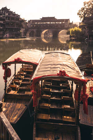 Feng Huang, China -  August 2019 :  Old historic wooden tourist boats on the riverbanks of Tuo river, flowing through the centre of Fenghuang Old Townのeditorial素材