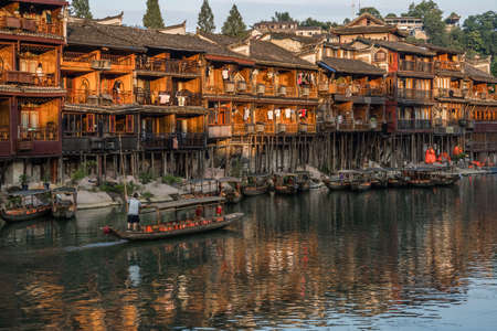 Feng Huang, China -  August 2019 : Old historic wooden tourist boat sailing on the Tuo river, flowing through the centre of Fenghuang Old Townのeditorial素材