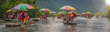 Yangshuo, China -  August 2019 : Panoramic view of tourists floating on bamboo rafts steered by...