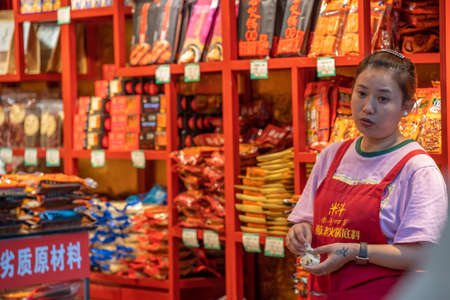Chongqing, China - August 2019 : Chinese woman selling snacks from her little shop on the street in Chongqing townのeditorial素材