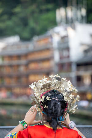 Feng Huang, China -  August 2019 : Chinese women dressed in traditional folk costume standing on the bridge and taking pictures of the Old Town in Fenghuang, Hunan Provinceのeditorial素材