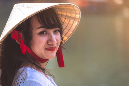 Feng Huang, China -  August 2019 : Cultural portrait of a beautiful chinese woman in a traditional triangular straw hat protecting from the sun and heatのeditorial素材