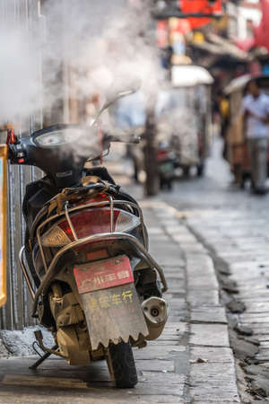 Yangshuo, China - August 2019 : Motorbike parked and leaned on a wall in Yangshuo Old Townのeditorial素材