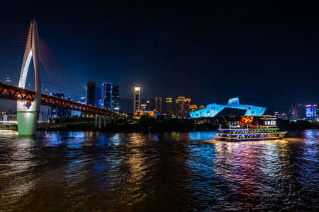 Chongqing, China -  August 2019 : Luxury passenger tourist ship cruising under Illuminated DongShuiMen road bridge over and across mighty Yangtze river in Chongqing town after  duskのeditorial素材
