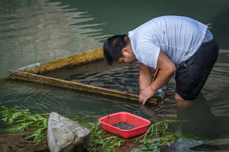 Feng Huang, China -  August 2019 : Feng Huang, China -  August 2019 : Chinese man washing plants and vegetables in the Tuo riverのeditorial素材