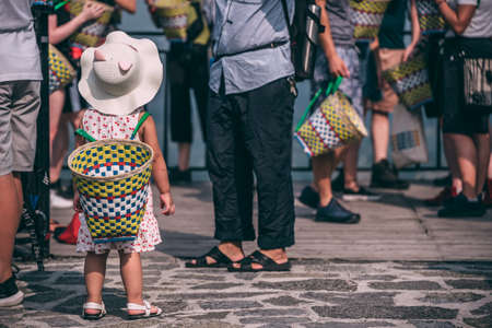 Yangshuo, China - August 2019 : Cute tiny chinese girl wearing large wicker basket on her back while...