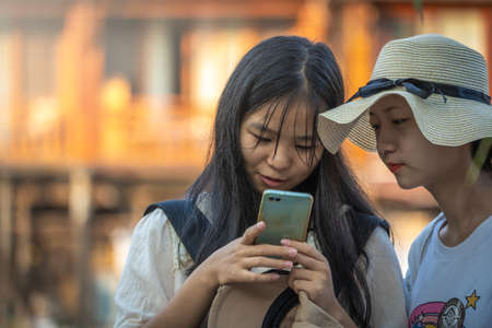 Feng Huang, China -  August 2019 :  Teenage chinese girl and her mother looking at the mobile phone,...