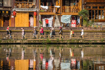 Feng Huang, China -  August 2019 : Reflection of people and tourists walking in front of traditional old wooden houses on the riverbanks of Tuo river, flowing through the centre of Feng huang Old Townのeditorial素材