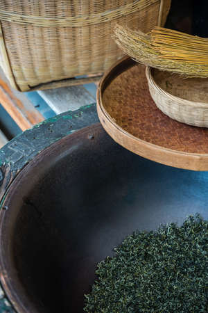 Vertical shot of woven baskets, broom and dried tea leaves in a huge bowl