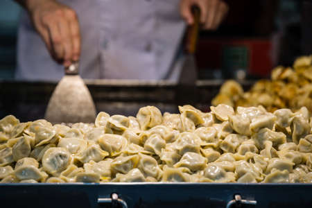 Delicious traditional chinese dumplings filled with pork meat, prepared on hot plate on a street stand, Chinaの写真素材