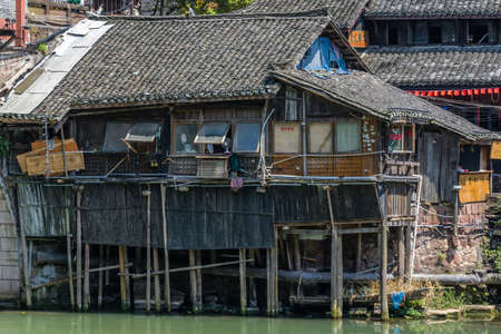 Feng Huang, China -  August 2019 : Smal old historic wooden Diaojiao house on the riverbank of Tuo river, flowing through the centre of Fenghuang Old Townのeditorial素材