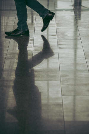 Floor reflection of the legs of traveller walking in airport lounge before departureの写真素材