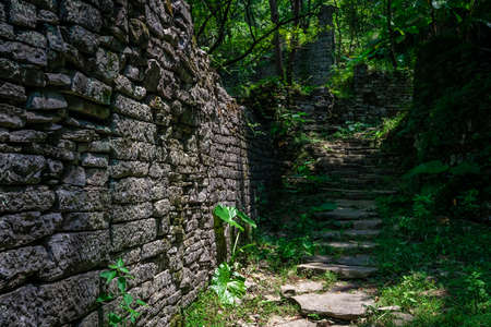 A pathway of concrete steps among old abandoned houses of an old village located in the middle of the lush tropical forest near Yangshuo, Chinaの写真素材