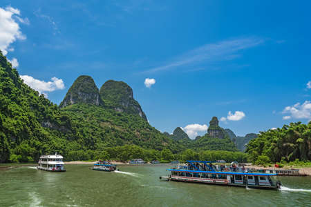 Yangshuo, China - August 2019 : Traffic of sightseeing boats carrying tourists sailing among stunning karst mountain scenery on the magnificent Li river between Guilin and Yangshuo townsのeditorial素材