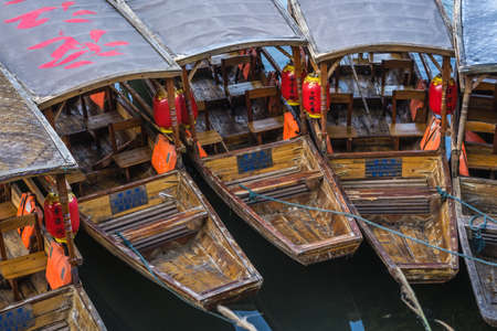 Feng Huang, China -  August 2019 : Close up of old historic wooden tourist boats moored on the...