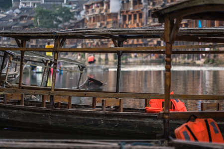 Close up of old historic wooden tourist boats moored on the riverbank of Tuo river, flowing through the centre of Fenghuang Old Townのeditorial素材
