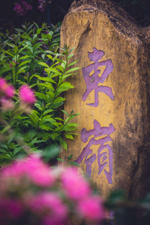 Yangshuo, China - August 2019 : Stone with chinese characters painted in purple colour in the gardenのeditorial素材